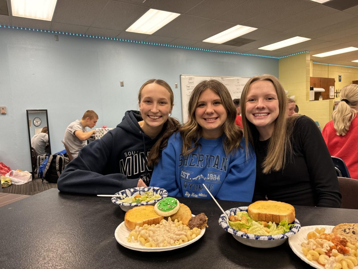 Devan Vinduska,  Lily Krainbill, and ____ enjoy their meal and the company of the camera.