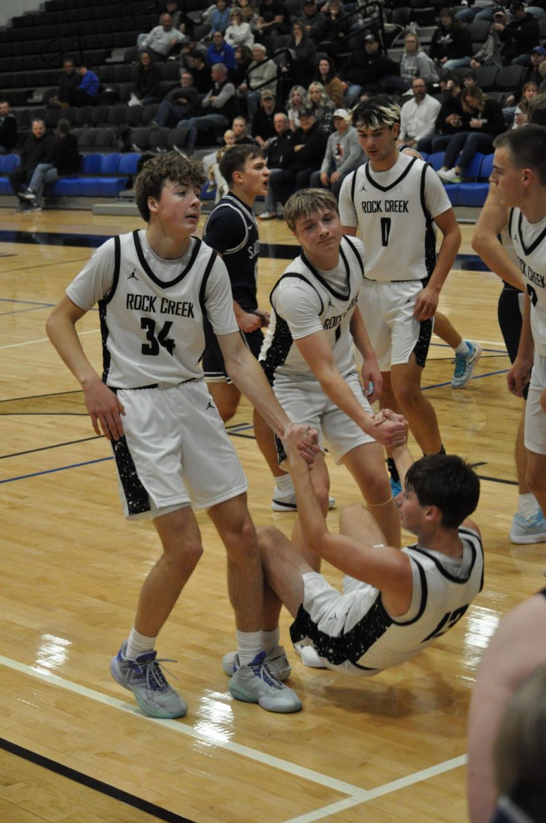 Giving a Helping Hand. Junior Logan Klingenberg (34) and senior Peter Martinie (0) lend a hand to junior Porter Gill (13). During the Sabetha game on December 18.